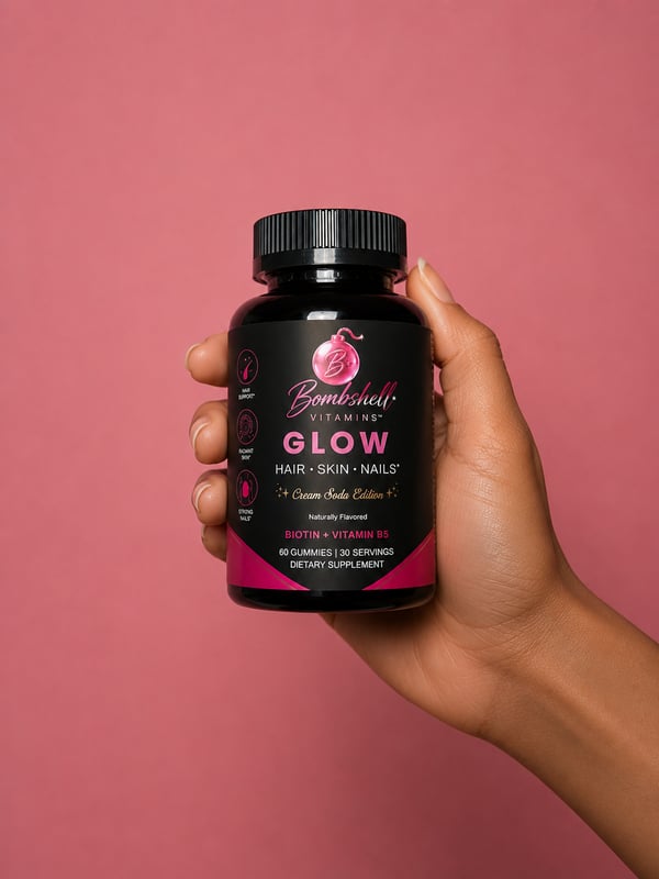A hand holding a bottle of Bombshell Glow against a pink background